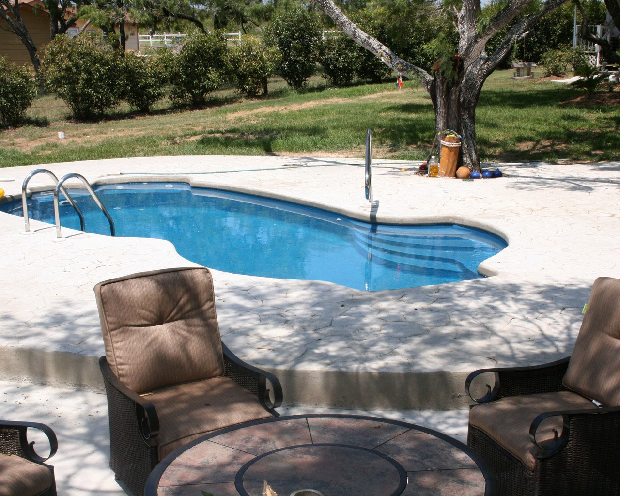 Beautiful Kingsbury pool style by Lonestar Fiberglass pools San Antonio with sublime stamped concrete pool deck, entry bar, and deep end exit ladder